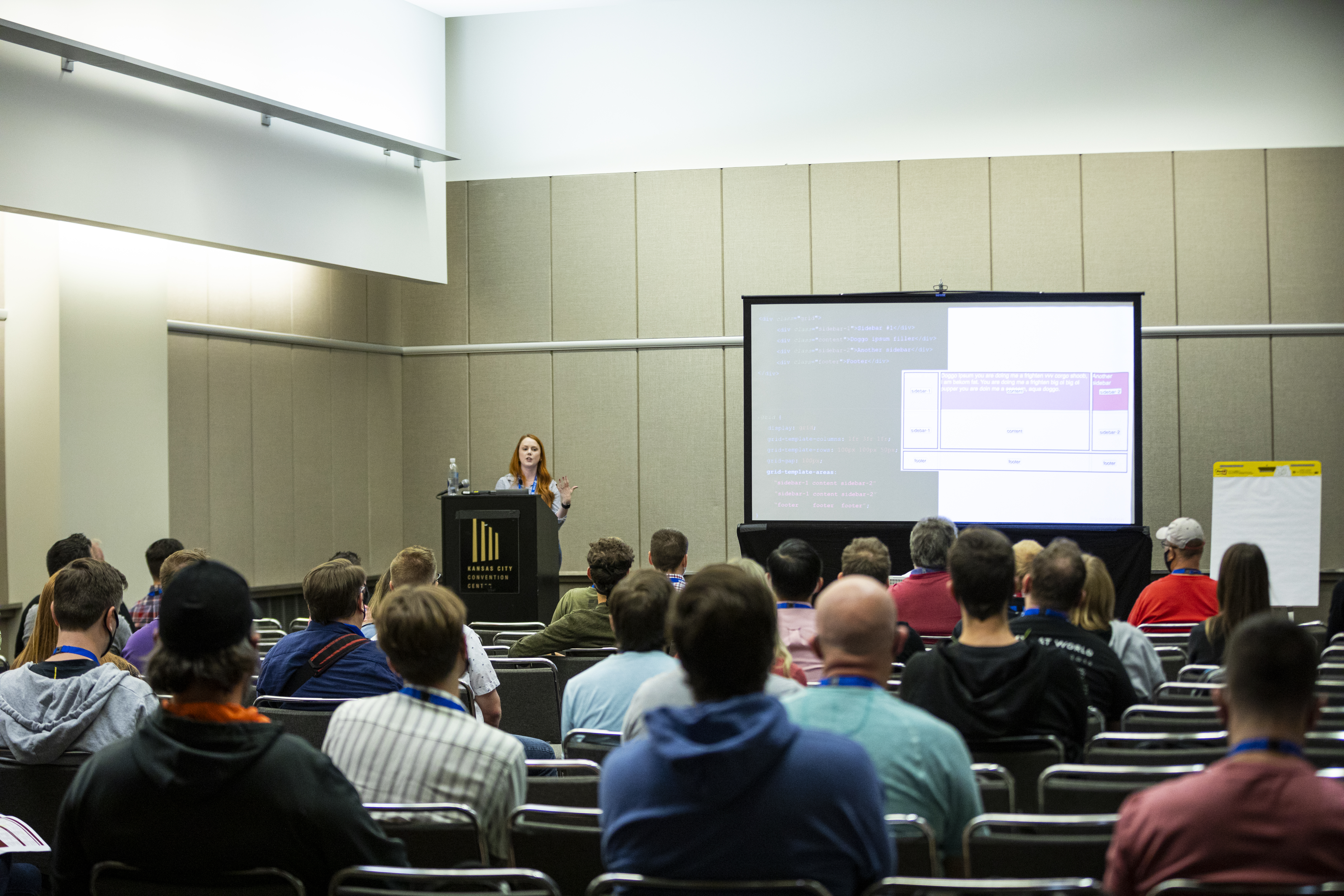 Kara standing at a podium giving a talk at the KCDC conference with attendees in the foreground.