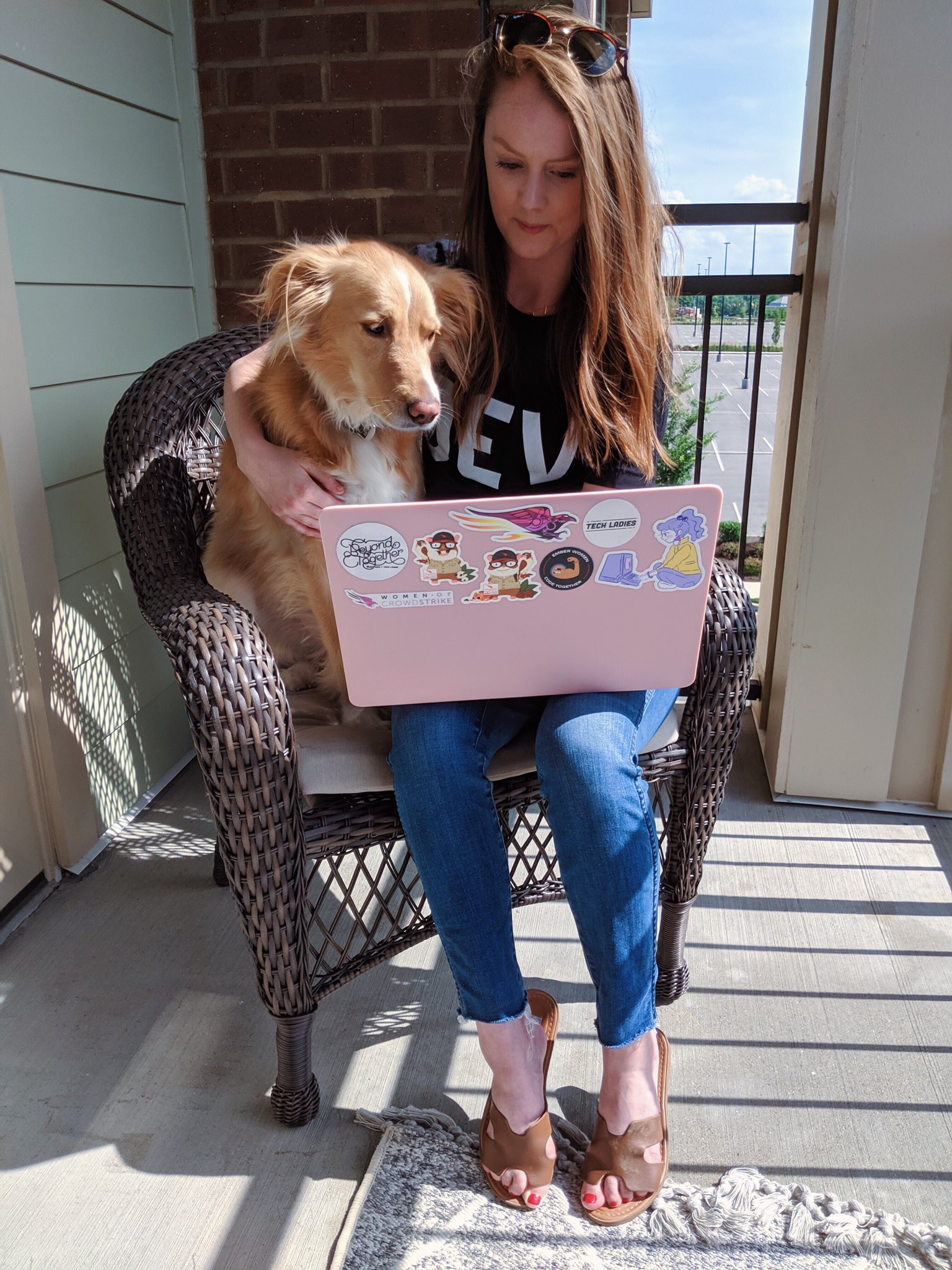 Kara with her dog, Maggie, sitting beside her on a chair both looking down at a laptop.